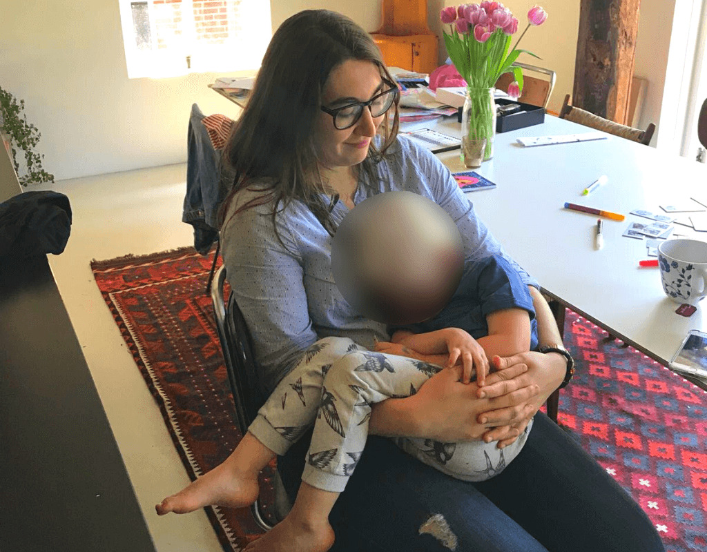 Kayla Ihrig as a nanny, sitting in a chair cradling a sleeping child