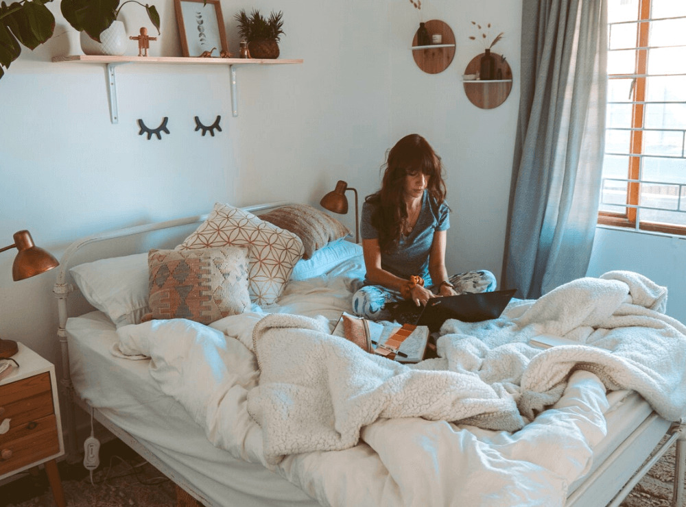 Woman sitting in bed writing on her laptop