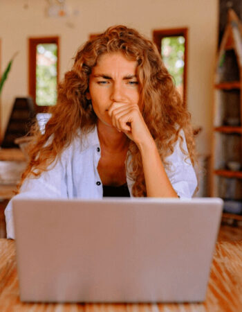 A woman sitting behind a laptop looking frustrated