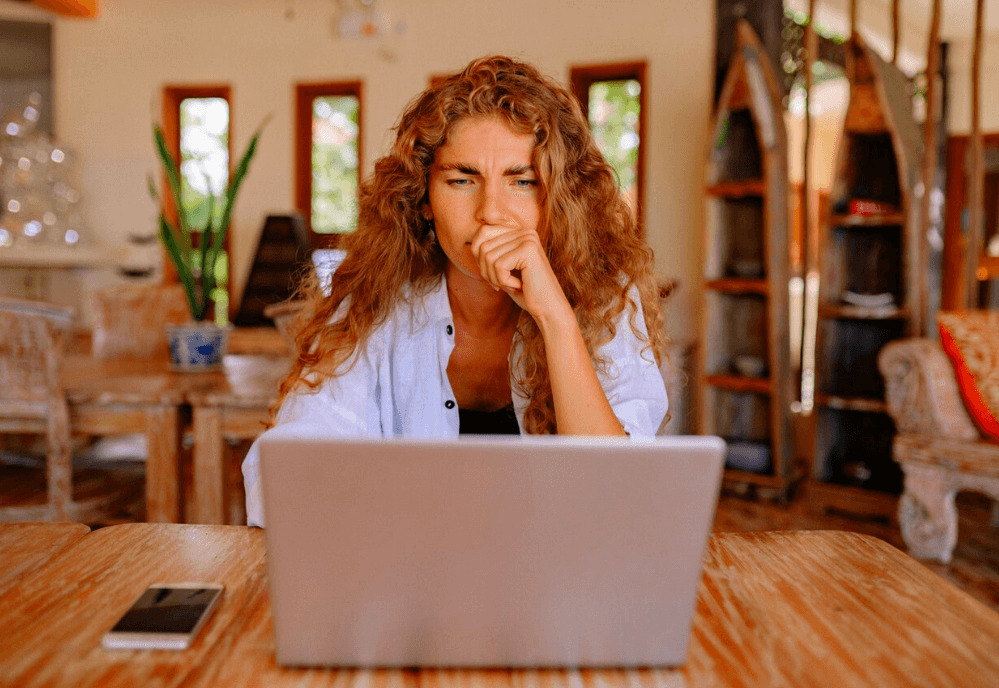 A woman sitting behind a laptop looking frustrated