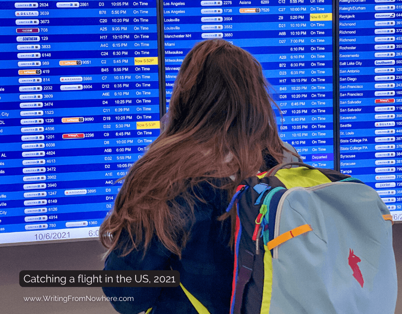 Woman wearing a backpack looking at a flight board at an airport