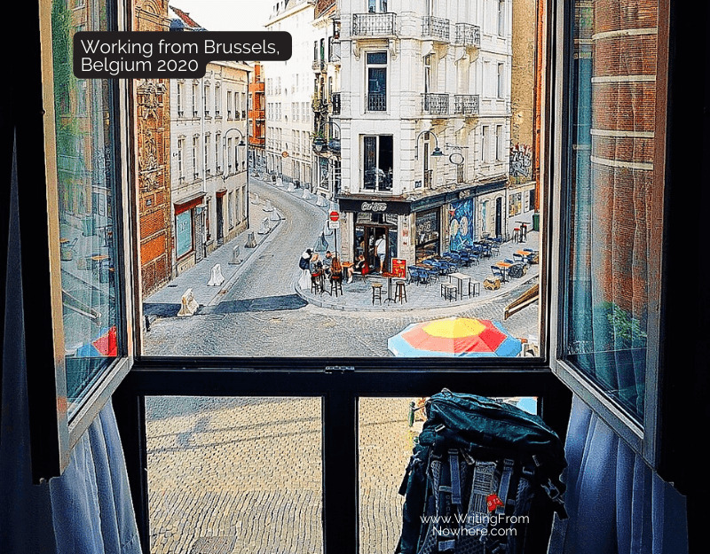 Open hotel window with a view of Brussels Belgium and a travel backpack propped up again the glass