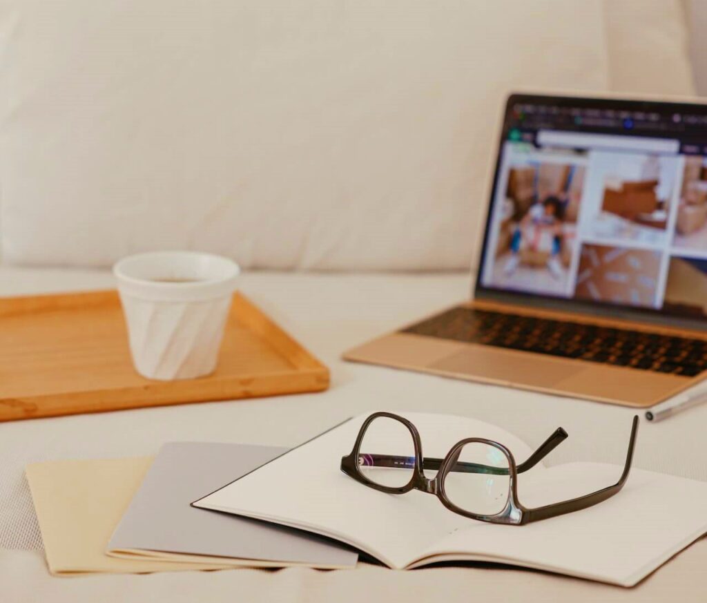 Glasses sitting on a notebook with a blurry laptop in the background